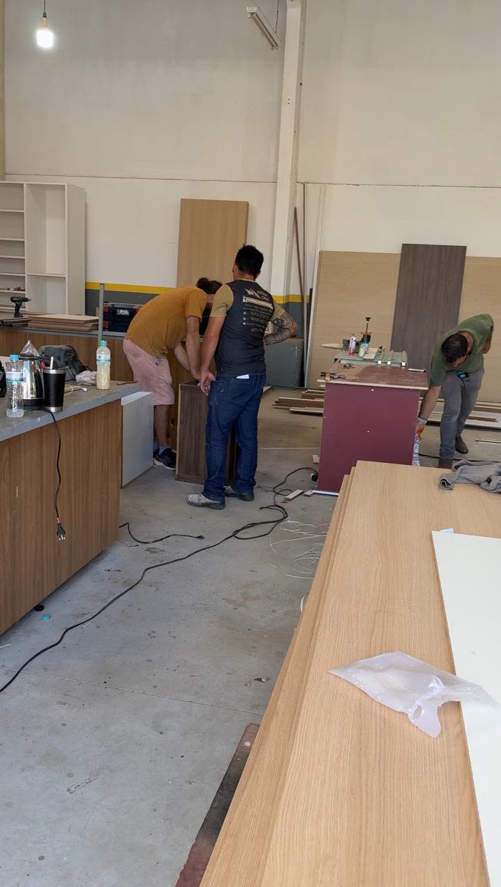 Equipe da D'Lócus trabalhando na fábrica em Itajaí, montando móveis sob medida entre painéis de madeira e MDF